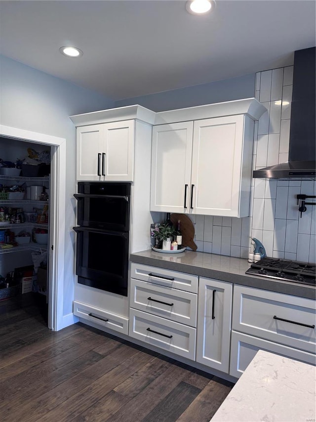 kitchen featuring white cabinetry, stainless steel gas cooktop, wall chimney exhaust hood, and double oven