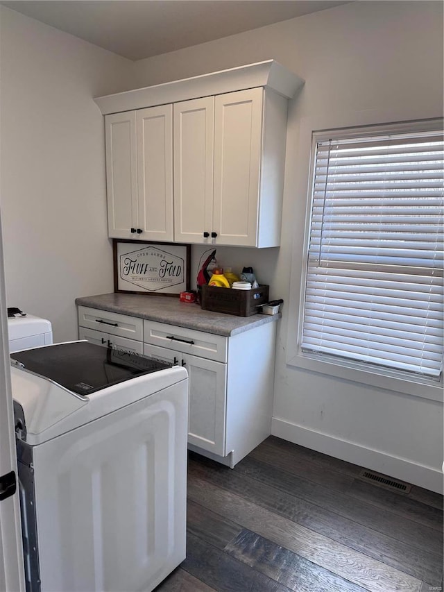 clothes washing area featuring cabinets, washing machine and dryer, plenty of natural light, and dark hardwood / wood-style flooring