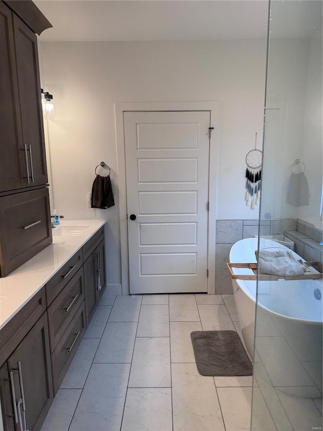 bathroom featuring vanity, tile patterned flooring, and tiled tub