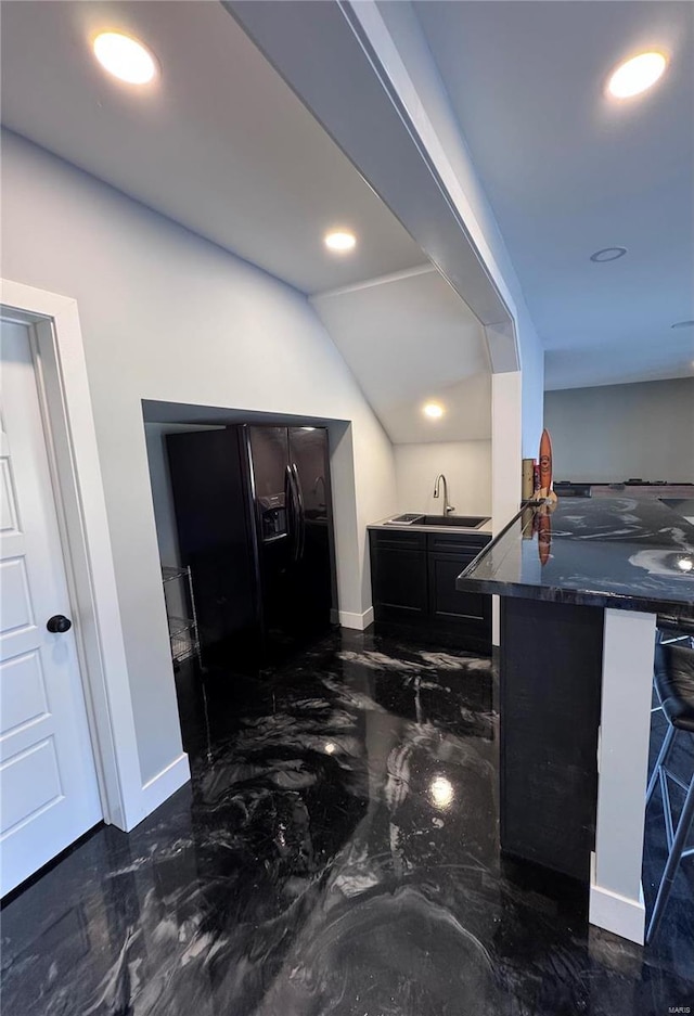 kitchen featuring black refrigerator with ice dispenser, sink, a kitchen bar, and kitchen peninsula