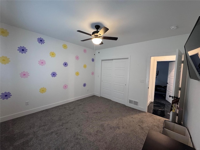 unfurnished bedroom featuring dark colored carpet, ceiling fan, and a closet