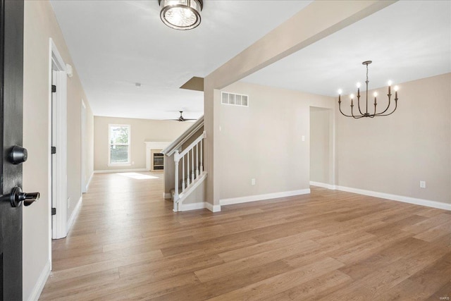 unfurnished room featuring visible vents, baseboards, stairs, light wood-type flooring, and a fireplace