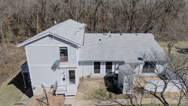 view of front of property featuring a shingled roof and a wooded view