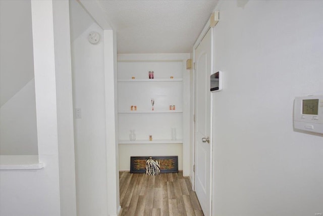 hall with a textured ceiling and wood finished floors