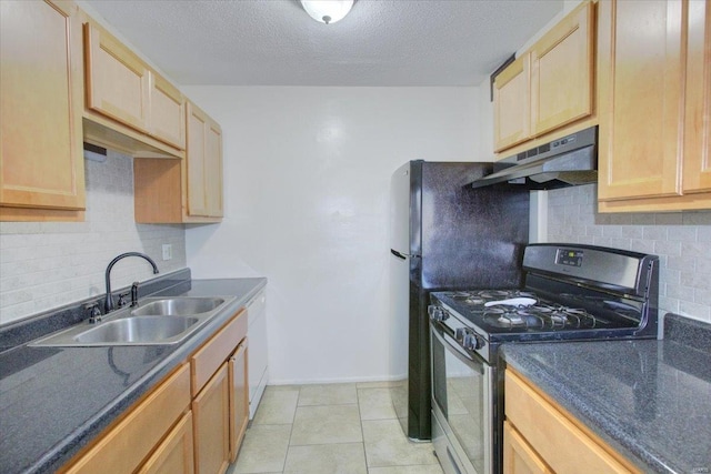 kitchen with dark countertops, gas range, under cabinet range hood, and a sink