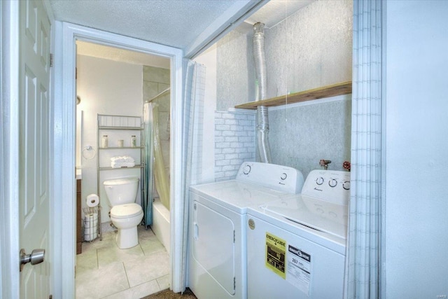 washroom with laundry area, a textured ceiling, washing machine and clothes dryer, and tile patterned floors