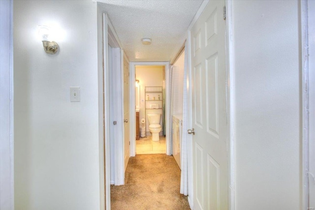 corridor featuring light carpet and a textured ceiling