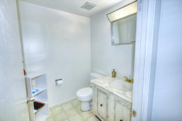 half bath featuring a textured ceiling, toilet, vanity, baseboards, and tile patterned floors