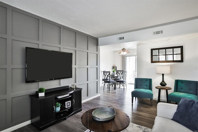 living room featuring ceiling fan, dark hardwood / wood-style floors, and a textured ceiling