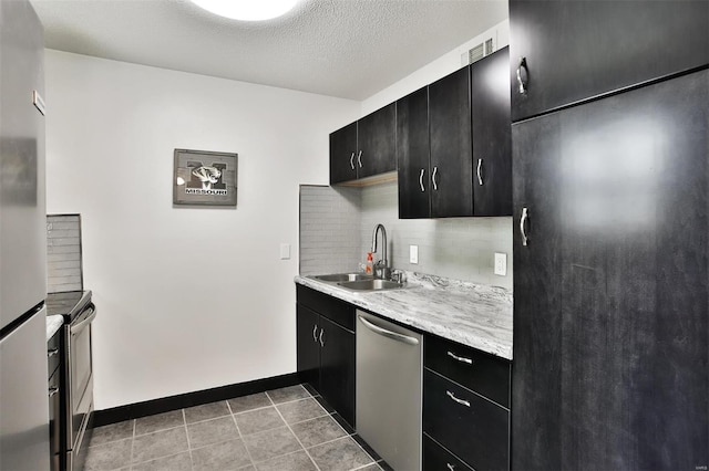 kitchen with light tile patterned flooring, sink, a textured ceiling, appliances with stainless steel finishes, and decorative backsplash