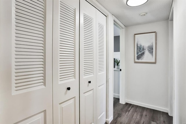 hall featuring dark wood-type flooring and a textured ceiling