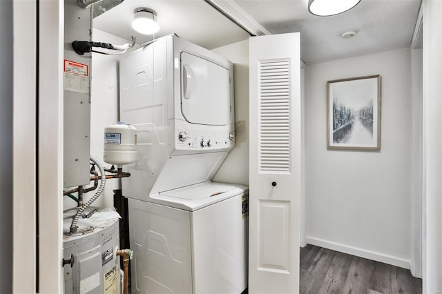 laundry room featuring stacked washer / dryer, hardwood / wood-style floors, and a textured ceiling