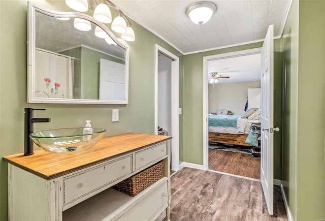 bathroom with ceiling fan, vanity, wood-type flooring, ornamental molding, and walk in shower