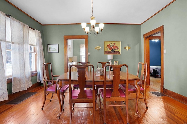 dining room featuring an inviting chandelier, hardwood / wood-style floors, and crown molding