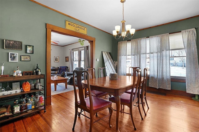 dining room with hardwood / wood-style flooring, crown molding, and a chandelier