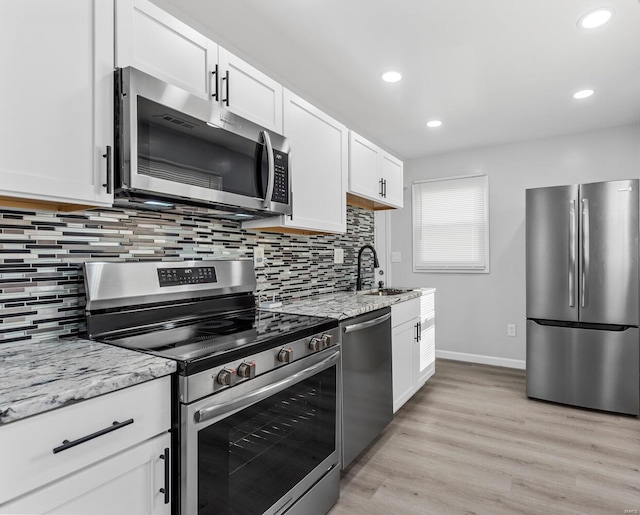 kitchen featuring sink, light stone counters, light hardwood / wood-style flooring, appliances with stainless steel finishes, and white cabinets