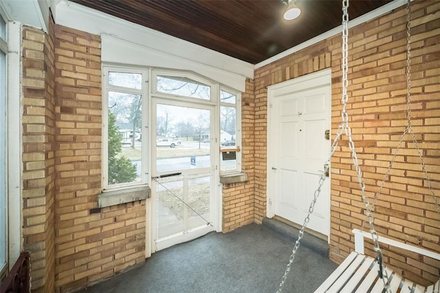 entryway with brick wall and dark carpet