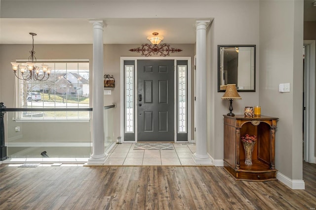 foyer entrance with hardwood / wood-style flooring, a chandelier, and ornate columns