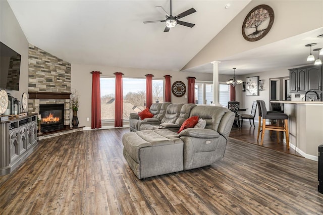 living room featuring ornate columns, dark wood-type flooring, ceiling fan with notable chandelier, and a fireplace