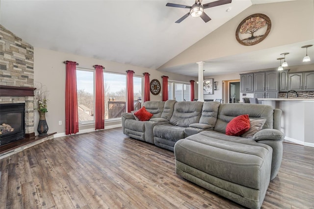 living room with sink, hardwood / wood-style flooring, ceiling fan, high vaulted ceiling, and a stone fireplace