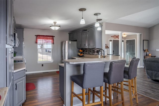 kitchen with stainless steel appliances, kitchen peninsula, decorative columns, and gray cabinetry