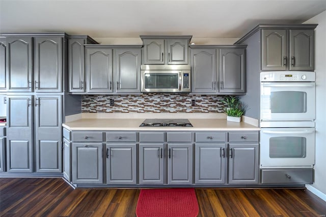 kitchen with double oven, dark wood-type flooring, gas stovetop, and gray cabinets