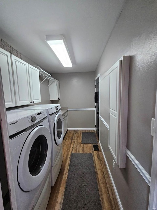 clothes washing area featuring cabinets, separate washer and dryer, and dark hardwood / wood-style flooring