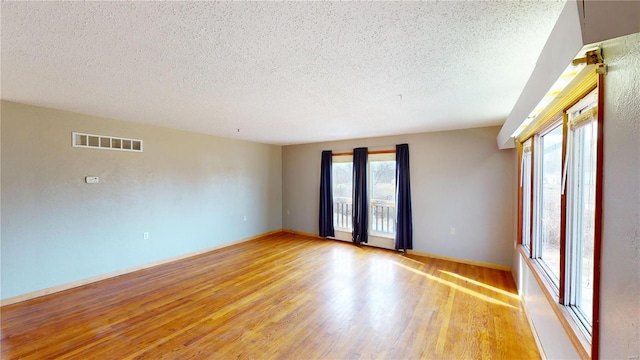 empty room with light hardwood / wood-style floors and a textured ceiling