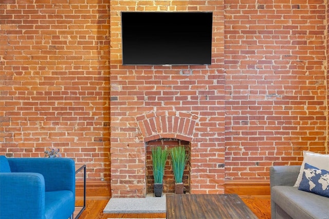 unfurnished living room featuring wood-type flooring and brick wall