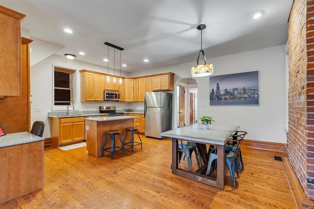 kitchen featuring pendant lighting, a kitchen island, a breakfast bar area, and appliances with stainless steel finishes