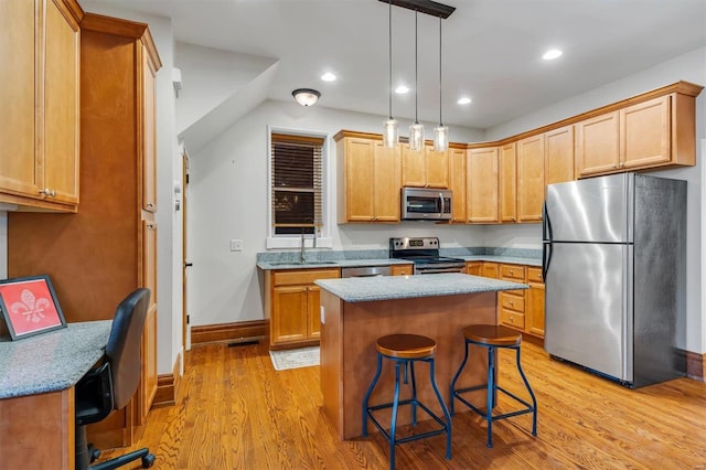 kitchen featuring a breakfast bar, decorative light fixtures, a center island, light wood-type flooring, and stainless steel appliances