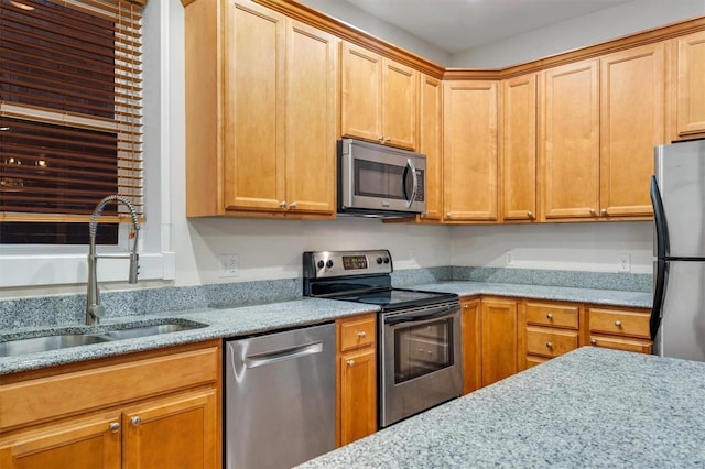 kitchen with light stone counters, sink, and appliances with stainless steel finishes