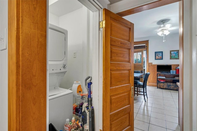 washroom with stacked washing maching and dryer, light tile patterned floors, and ceiling fan