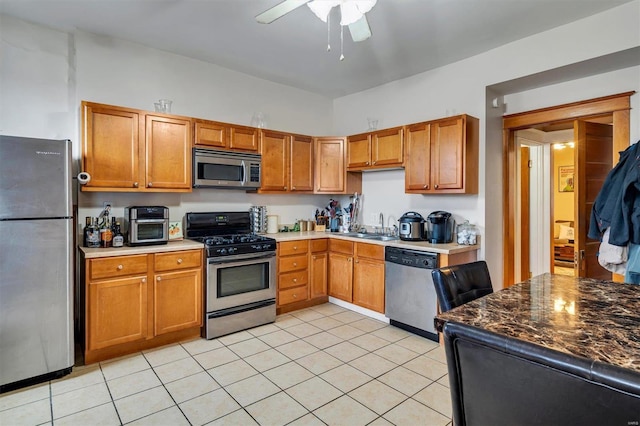 kitchen with light tile patterned flooring, appliances with stainless steel finishes, sink, and ceiling fan