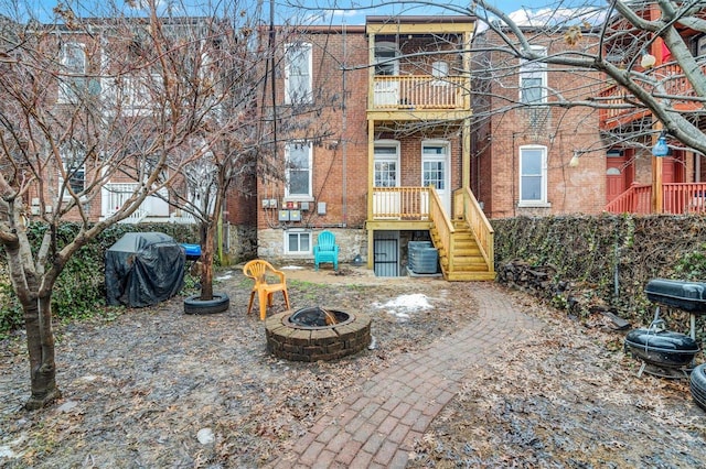 rear view of property with a balcony, central air condition unit, and a fire pit