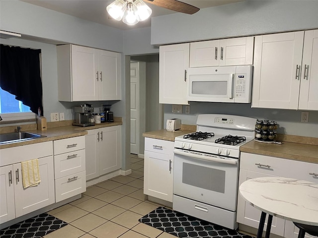 kitchen with white cabinetry, sink, light tile patterned floors, and white appliances