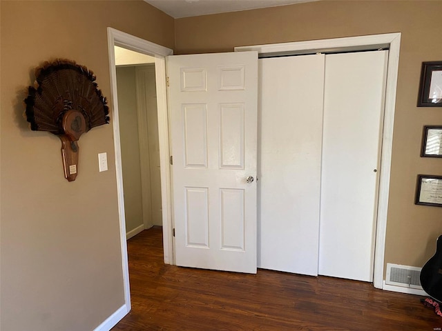 unfurnished bedroom with dark hardwood / wood-style flooring and a closet