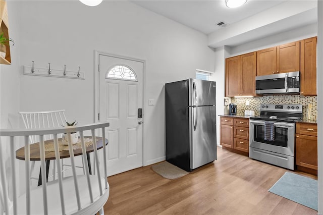 kitchen with decorative backsplash, stainless steel appliances, and light hardwood / wood-style floors