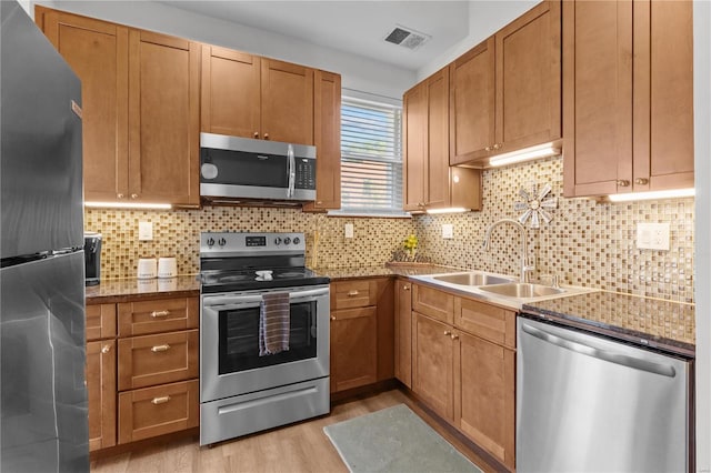 kitchen featuring light stone counters, stainless steel appliances, light hardwood / wood-style floors, and sink