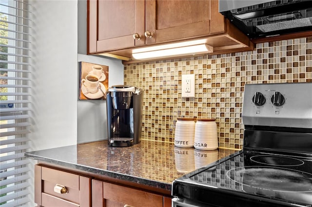 kitchen with backsplash, dark stone counters, and stainless steel range with electric stovetop