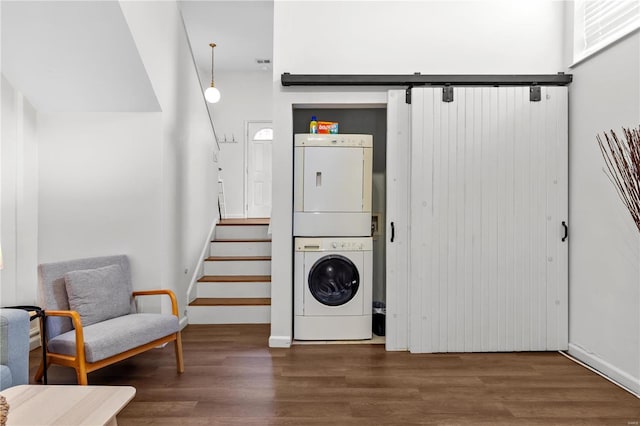 washroom with stacked washer and dryer and dark hardwood / wood-style flooring