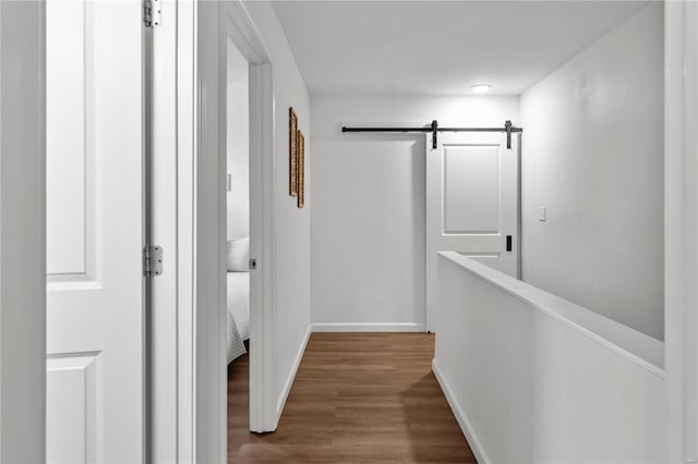 hall with wood-type flooring and a barn door