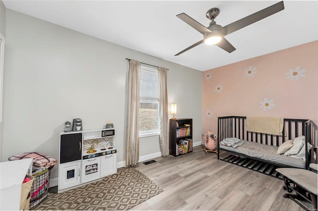 bedroom with light wood-style floors, visible vents, ceiling fan, and baseboards