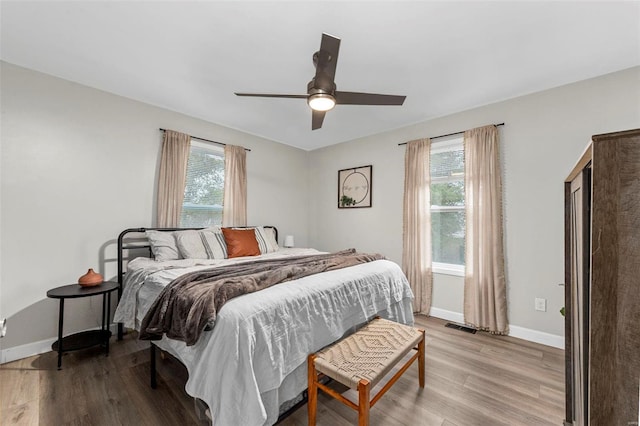 bedroom featuring light wood-style floors, visible vents, multiple windows, and baseboards