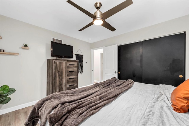 bedroom with ceiling fan, wood finished floors, visible vents, and baseboards