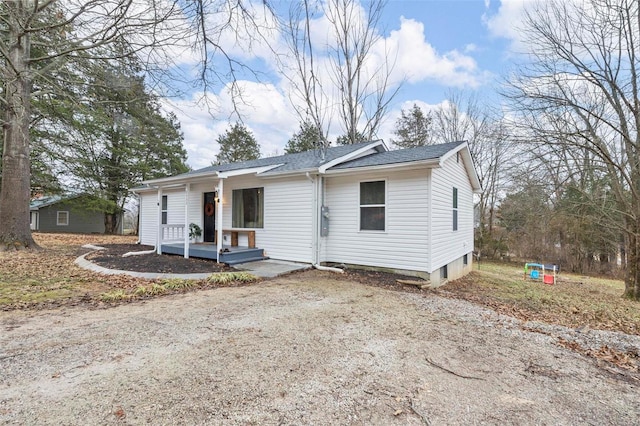 view of front of home with a porch, a shingled roof, and dirt driveway