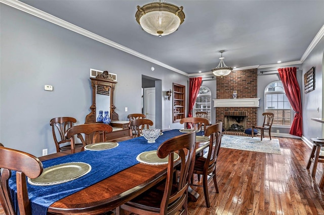 dining area featuring hardwood / wood-style flooring, crown molding, and a brick fireplace