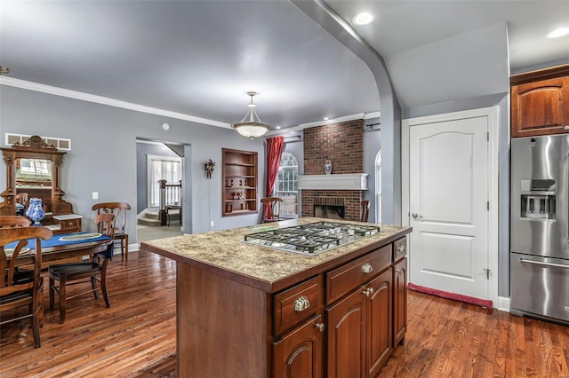 kitchen with dark hardwood / wood-style floors, appliances with stainless steel finishes, decorative light fixtures, and a center island