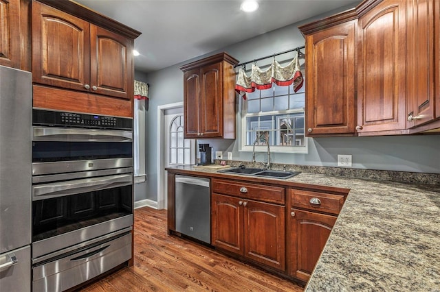 kitchen featuring light stone counters, stainless steel appliances, dark hardwood / wood-style floors, and sink