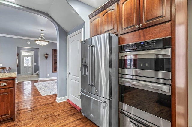 kitchen with ornamental molding, dark wood-type flooring, stainless steel appliances, and vaulted ceiling